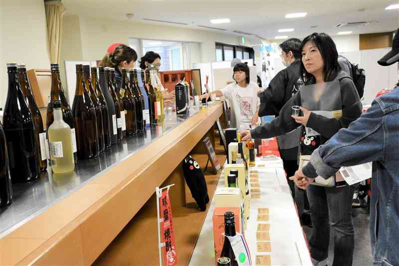 熊本の飲食物や観光情報をPRするイベントで、球磨焼酎の試飲を楽しむ買い物客＝14日、札幌市