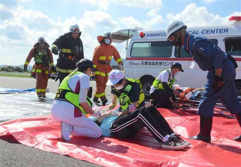 航空機事故を想定した訓練で、負傷者の救助やトリアージの手順を確認する参加者＝15日、天草市