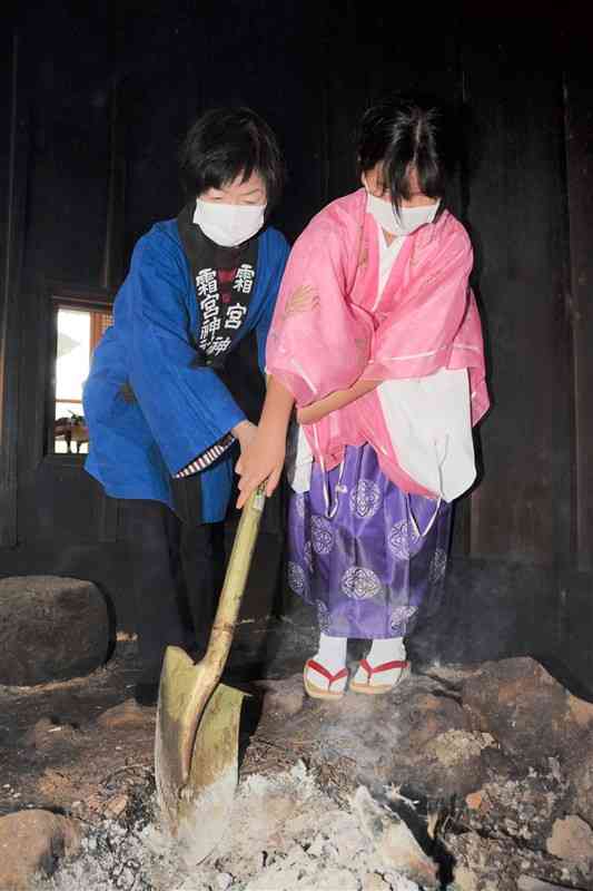 ご神体を温めていた火を消す火焚き乙女の山部結愛さん（右）＝阿蘇市