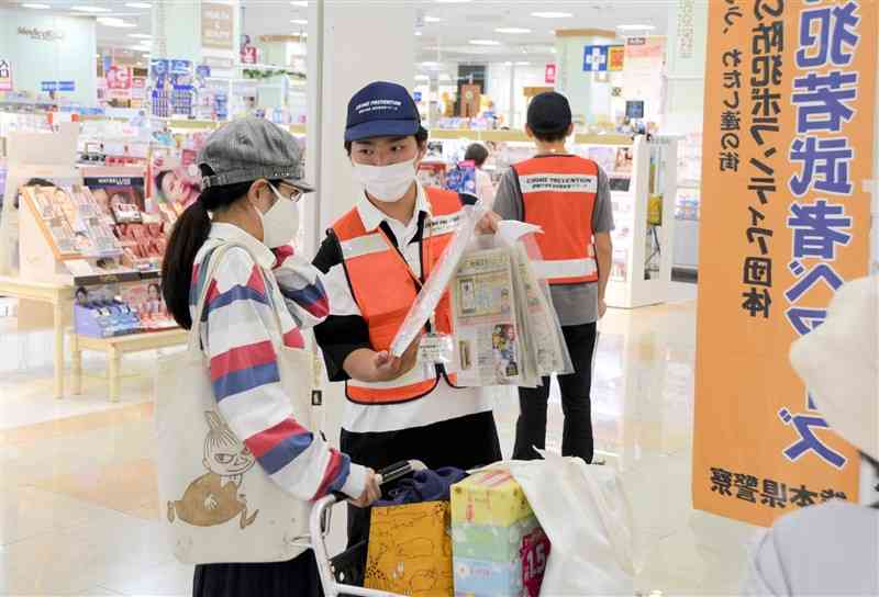 買い物客に詐欺被害防止を呼びかける「防犯若武者ベアーズ」のメンバー（中央）＝15日、熊本市南区