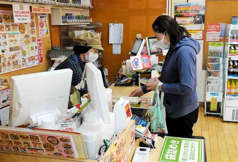 おべんとうのヒライ東町店のレジで接客するパート従業員の女性。「年収の壁」を意識して働く時間を調整しているという＝18日、熊本市東区