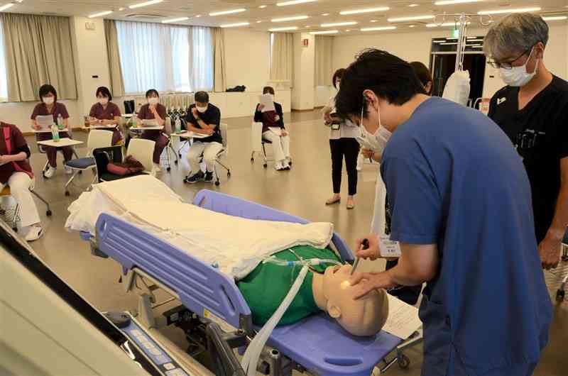 人形を使い、脳死判定の手順を確認する済生会熊本病院の医師や看護師ら＝18日、熊本市南区