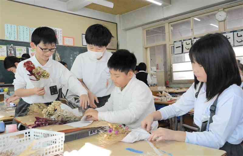ドライフラワーのスワッグを作る一新小の3年1組の子どもたち＝30日、熊本市中央区