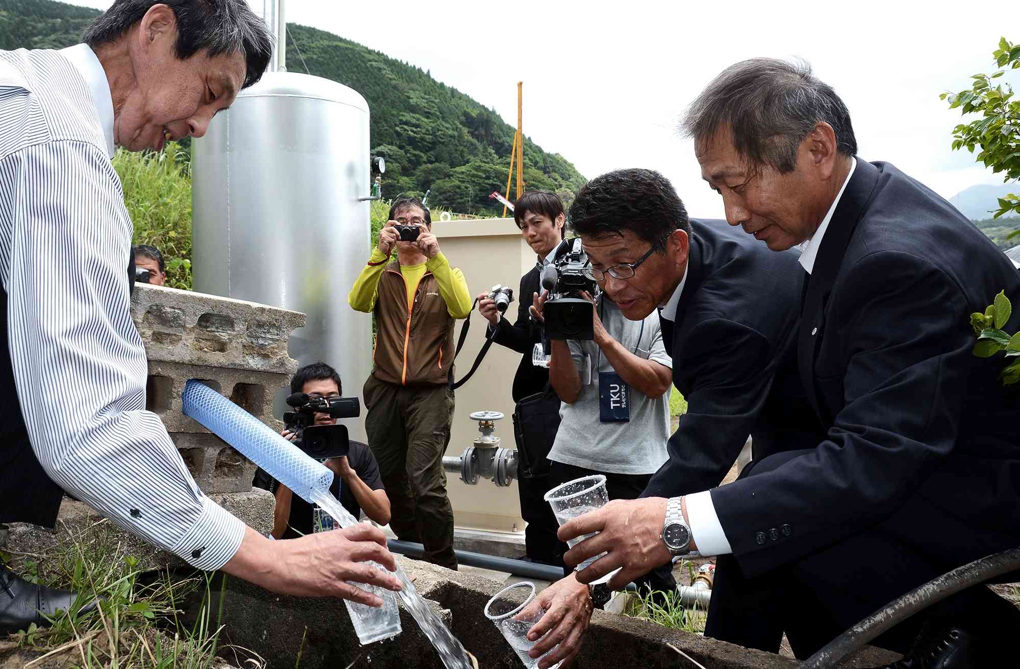 東京エレクトロン九州が南阿蘇村に寄贈した井戸の水を飲む筆者ら（左端）