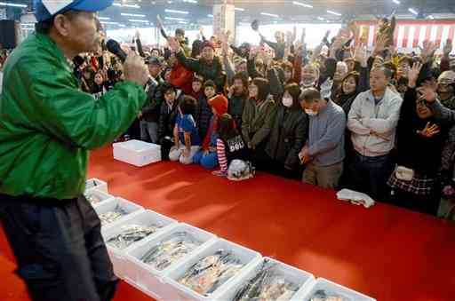 鮮魚の模擬競りで、競り人の呼び掛けに応じて一斉に手を挙げる客たち＝2018年12月2日、熊本市