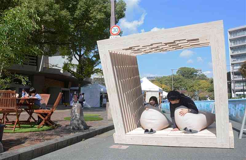車両通行止めにした市民会館前の市道に設置されたオブジェで遊ぶ親子＝28日、熊本市中央区