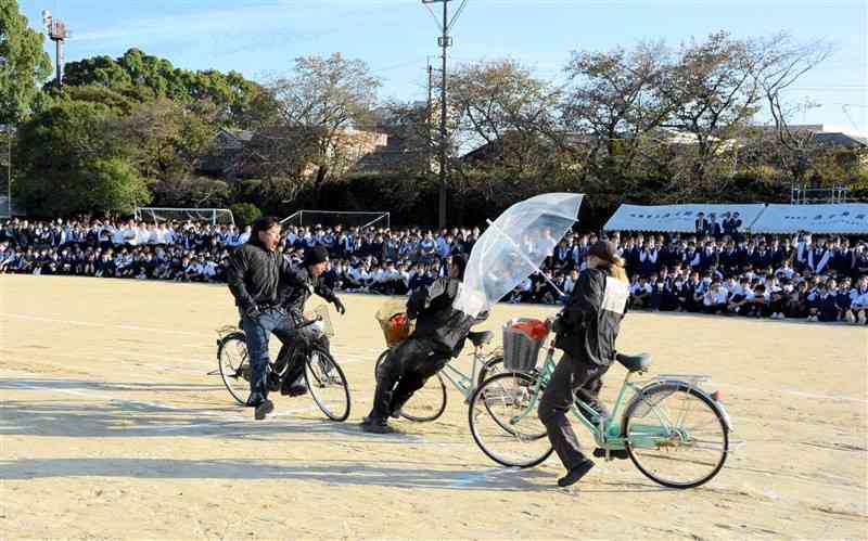 済々黌高の生徒を前に自転車同士の交通事故を再現するスタントマン＝9日、熊本市中央区