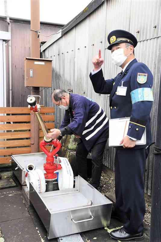 八千代座への特別査察で、屋外の放水銃を確認する山鹿市消防本部の有尾壽郎消防長（右）＝10日、山鹿市