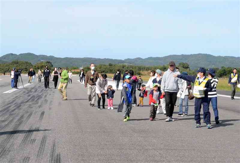 全長1キロの滑走路を、路面の表示や飛行機のタイヤの跡などに注目しながら歩く参加者＝11日、天草市