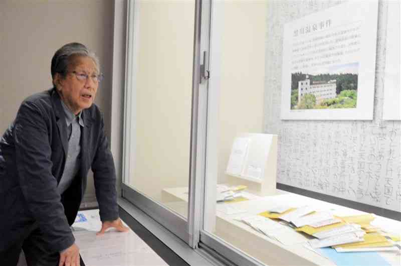 菊池恵楓園の歴史資料館に展示された宿泊拒否事件での「差別文書」を前に、当時を振り返る入所者自治会の太田明副会長＝10日、合志市