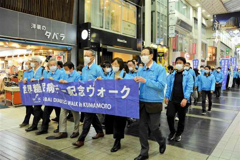 横断幕やのぼりを手に上通アーケードをパレードする参加者＝14日、熊本市中央区