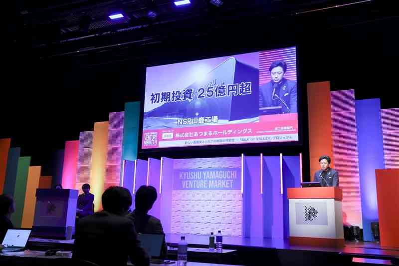 養蚕事業について説明する「あつまるホールディングス」の島田裕太専務（右）＝14日、福岡市（九州・山口ベンチャーマーケット実行委提供）