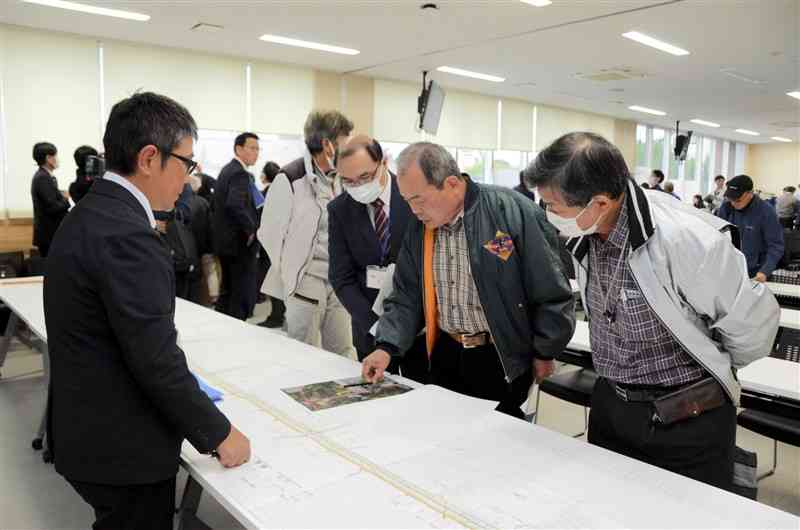 道路整備事業の説明会で図面を確認する出席者ら＝17日、菊陽町