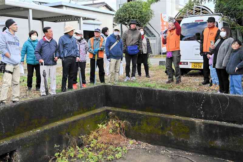 通信教育隊の風呂場跡を見学するフットパスの参加者＝18日、菊池市