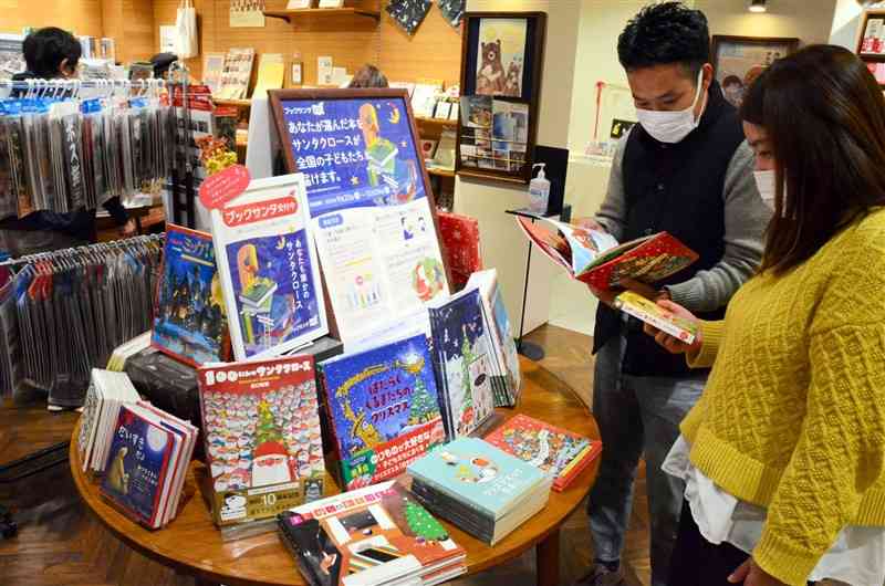 ブックサンタの特設コーナーで本を選ぶ夫婦＝11月27日、熊本市中央区の長崎書店