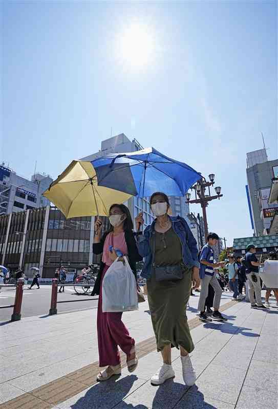 厳しい暑さの中、日がさを差して歩く人たち＝7月、東京・浅草