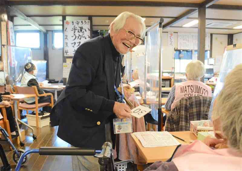 「松本カレッジ」でデイサービスの利用者に笑顔で語りかける松本和良さん＝11月22日、熊本市南区