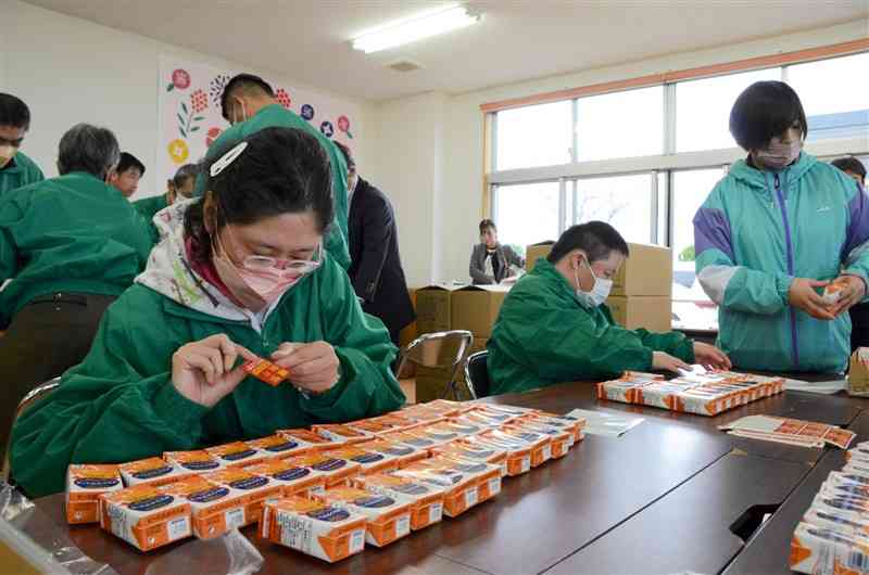 ジュースに年賀シールを貼る「熊本菊陽学園」の利用者ら＝11月30日、菊陽町