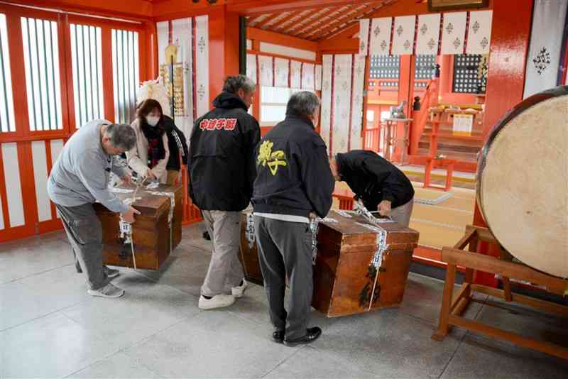 八代妙見祭の「注連納」で獅子舞の道具を入れた木箱を運び込む関係者ら＝1日、八代市