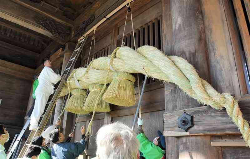 阿蘇神社の楼門に大しめ縄を飾り付ける「一の宮町大注連縄伝承会」の会員ら＝4日、阿蘇市