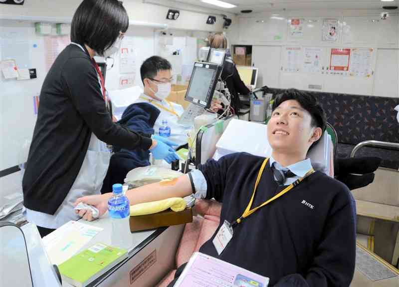 文徳高に出向いた献血バスの中で献血する生徒＝11月8日、熊本市西区