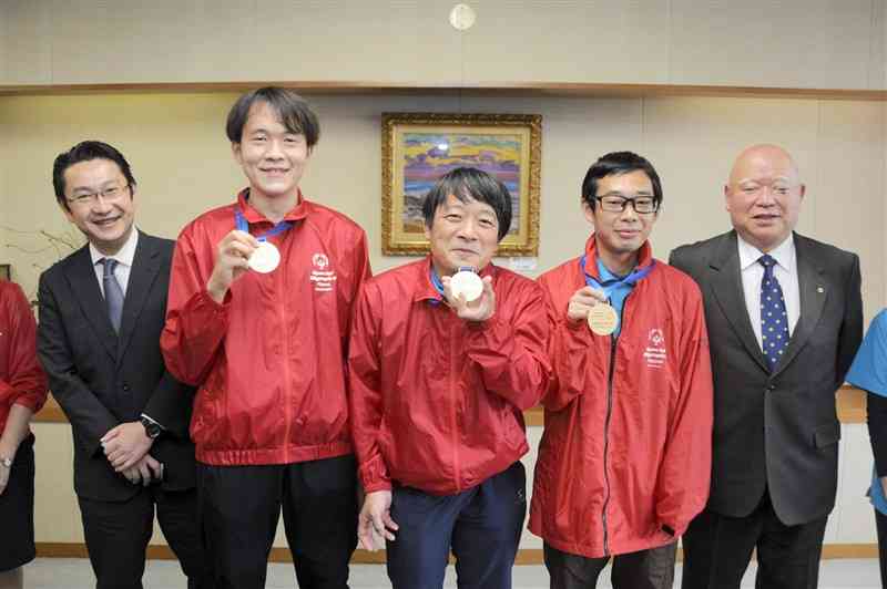 スペシャルオリンピックス日本冬季大会で獲得したメダルを掲げる選手たち＝11日、熊本市役所