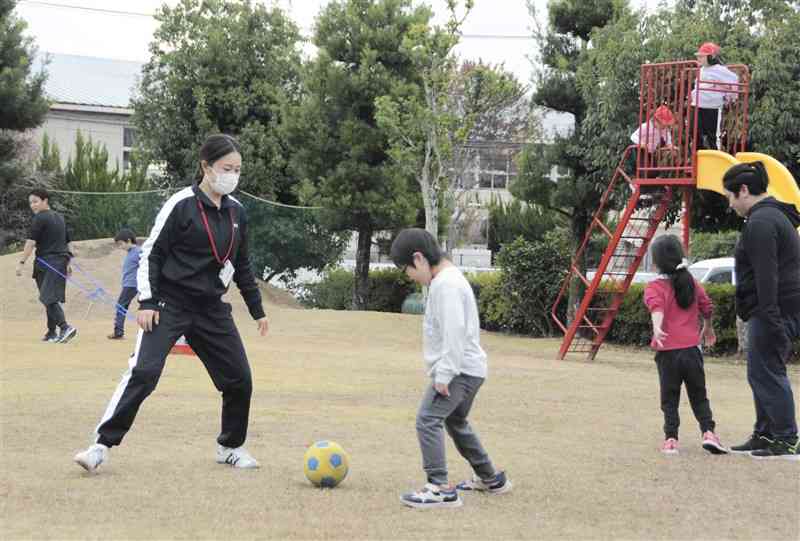 昼休み中に熊本支援学校小学部の児童とサッカーを楽しむ九州ルーテル学院大の大塚倫加さん（手前左）＝14日、熊本市中央区