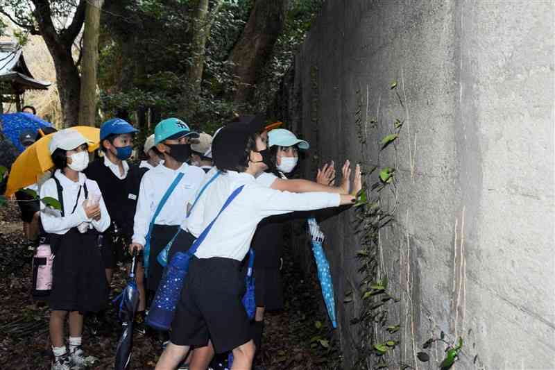菊池恵楓園内に残る「隔離の壁」を見学する合志楓の森小の児童たち＝15日、合志市