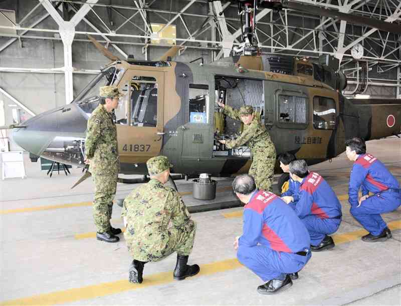 陸上自衛隊ヘリコプターの災害時の役割や性能を学ぶ熊本県職員ら＝15日、益城町