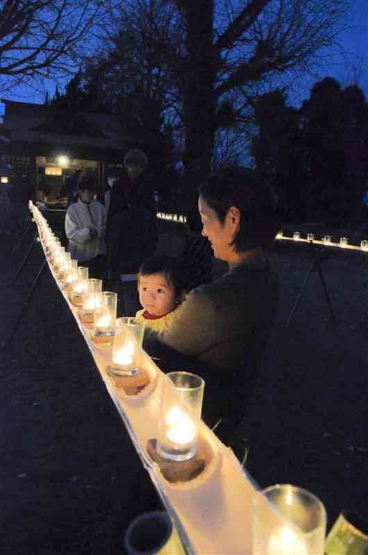 地区住民らが竹の上にろうそくをともした熊野坐神社の「千灯明」＝15日、益城町