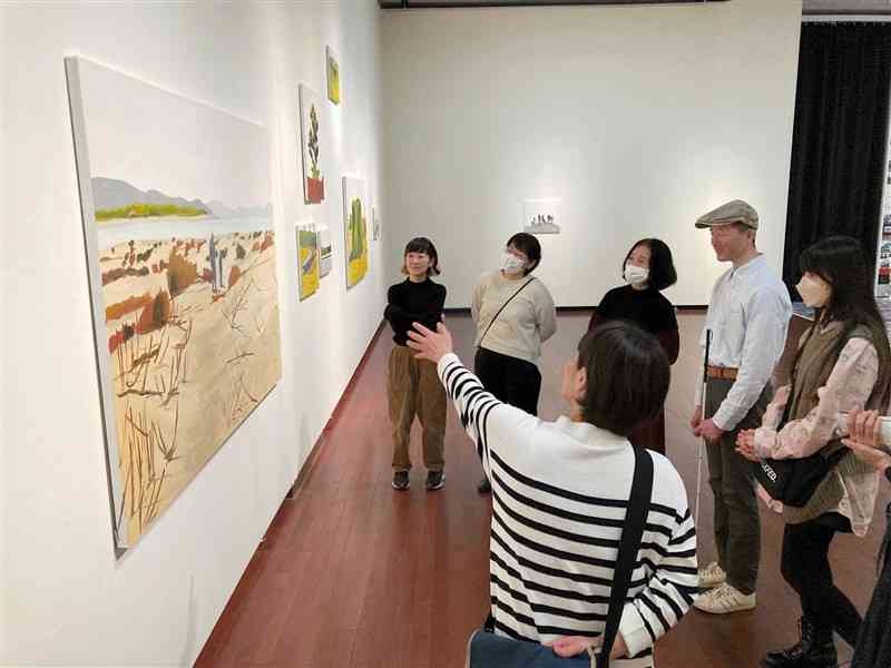 「遠距離現在」展を鑑賞する白鳥建二さん（右から2人目）ら＝16日、熊本市中央区