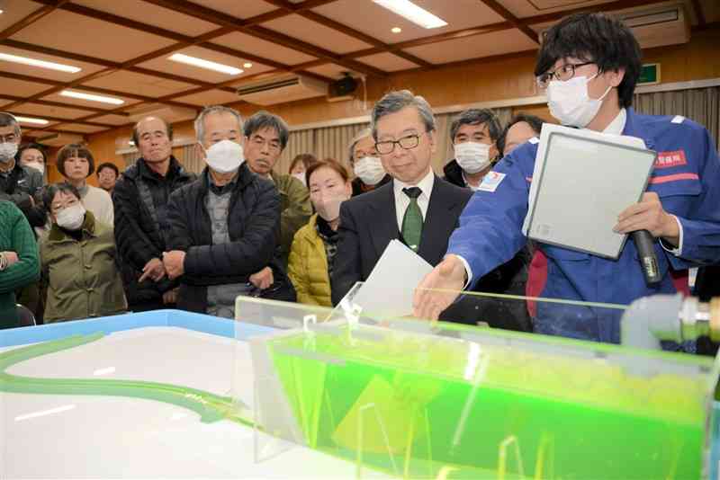 模型を使い、流水型ダムの操作について住民に説明する国土交通省の担当者（右）＝16日、相良村総合体育館