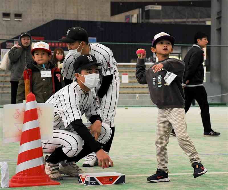 高校生からボールの投げ方を教わる子どもたち＝17日、熊本市東区
