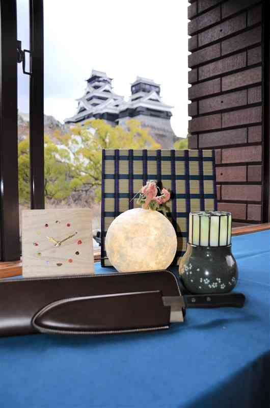 県内の伝統工芸家が県外のクリエーターと共同開発した包丁のレザーケース（手前）や桐時計（左）、龍神と和紙の灯りのオブジェ（中央）など＝22日、熊本市中央区