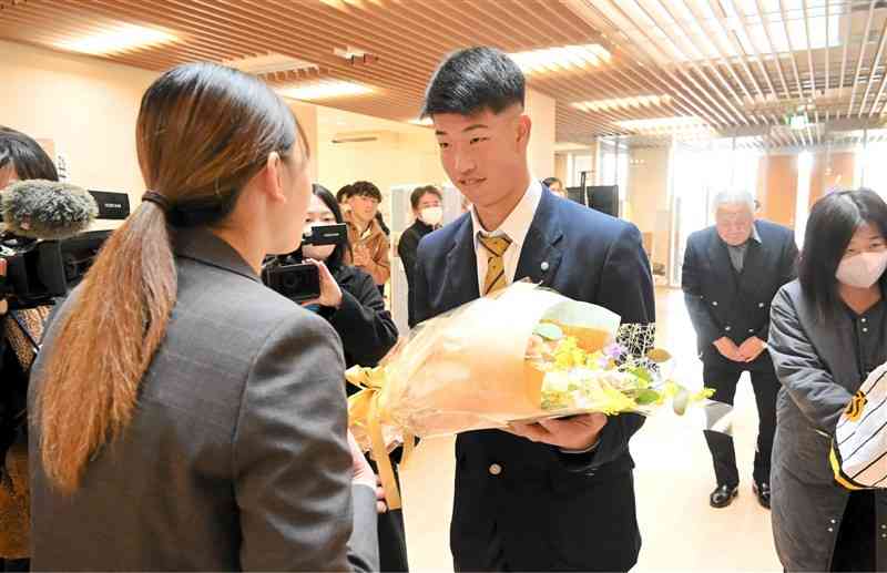 菊池市役所で職員から花束を贈られる百﨑蒼生選手＝22日、同市