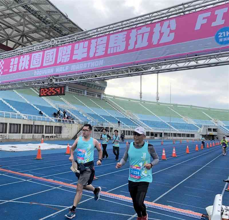 桃園国際シティハーフマラソンでゴールする玉名市からの出場者（左）＝23日、台湾・桃園市