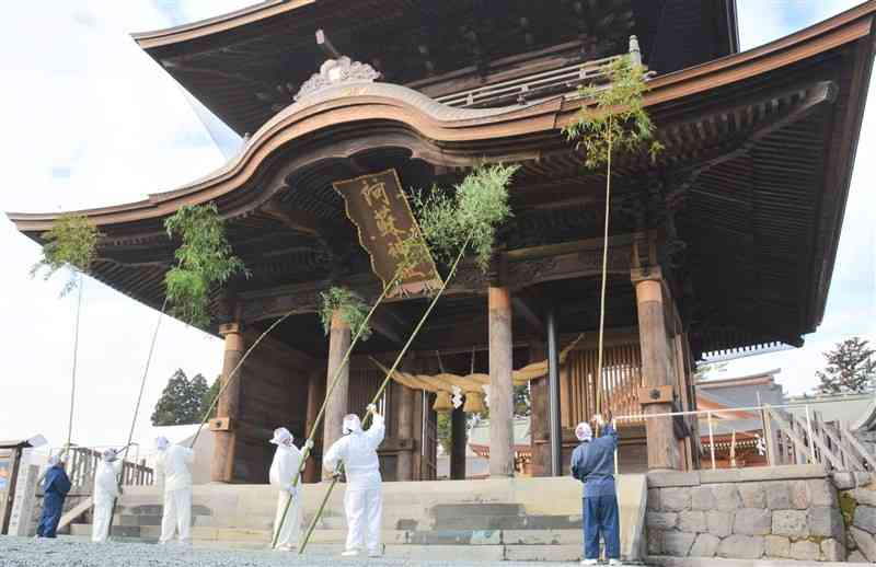 阿蘇神社の楼門を葉を残した竹で清める神職たち＝26日、阿蘇市