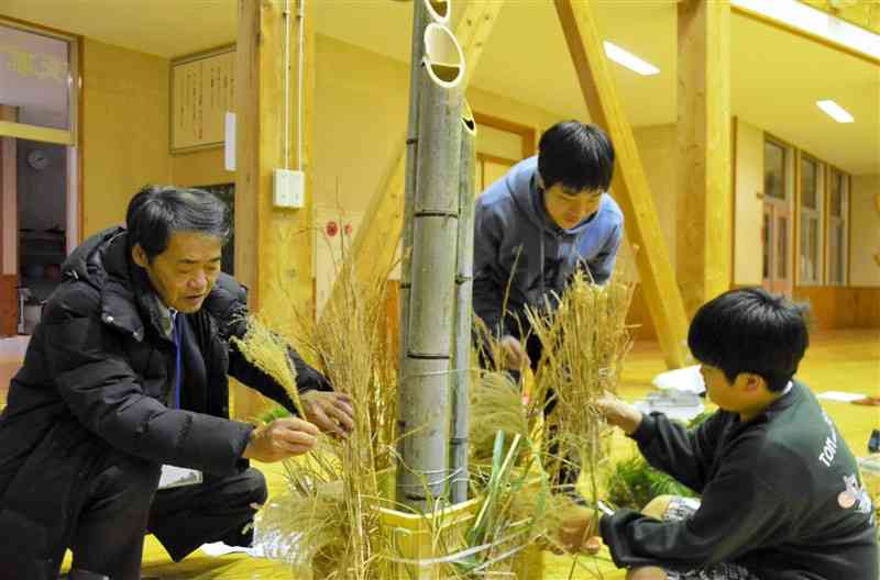 熊本学習支援センター天草下田南校で、新年に飾る門松を作る男子中学生と仙波達哉さん（左）＝昨年12月、天草市