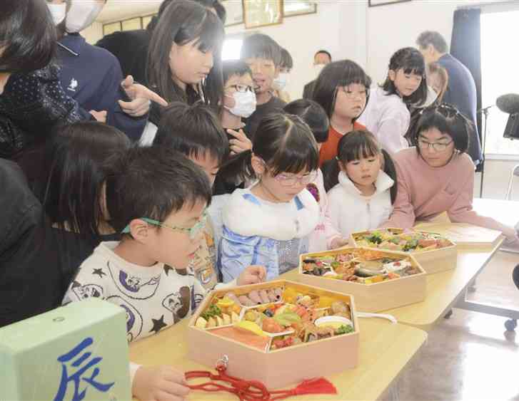 熊本ホテルキャッスルから贈られたおせち料理をのぞき込む子どもたち＝31日、熊本市中央区