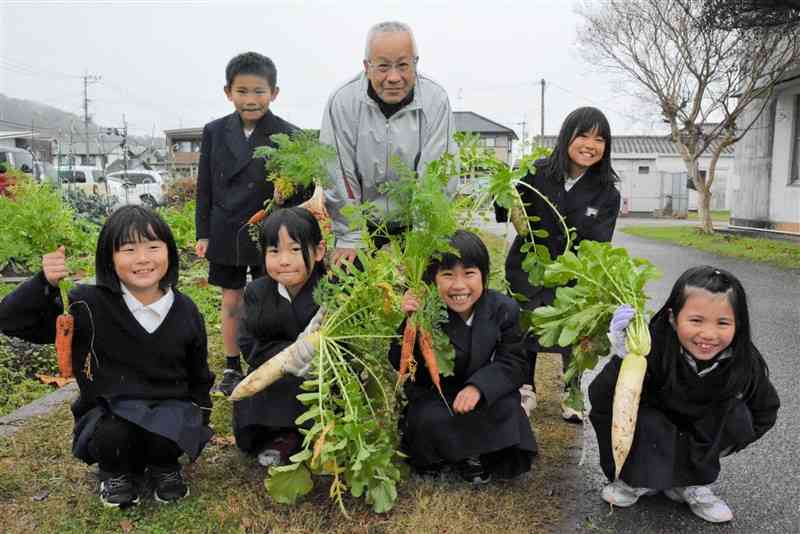 野菜づくりを通じ、松橋小の児童に食の大切さを伝える丘寛史さん（後列中央）＝宇城市