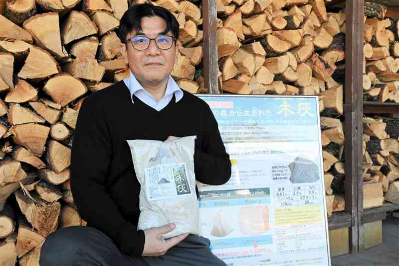 木灰のサンプルを持つ九州バイオマスフォーラムの中坊真事務局長＝12月27日、阿蘇市