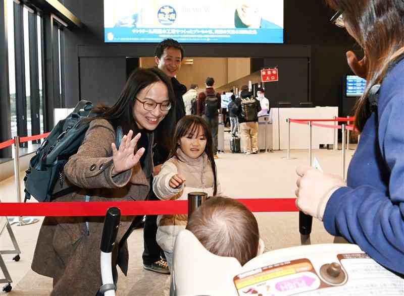 熊本空港国内線ターミナルで、親せきの見送りに手を振る家族連れ＝3日午前9時15分ごろ、益城町（石本智）