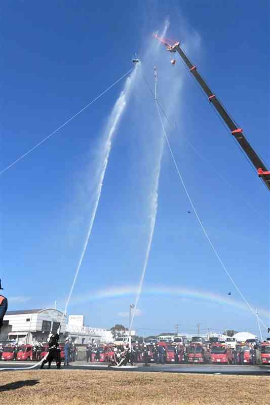 地上20メートルにつり上げたかごのボールを目がけて放水する消防団員たち＝4日、上天草市