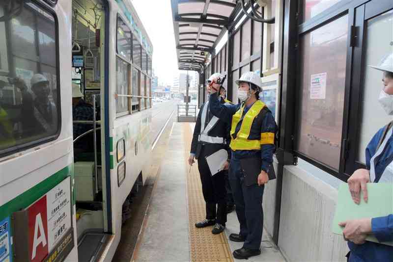 当該車両と同型の熊本市電を写真に収める鉄道事故調査官ら＝6日、熊本市中央区