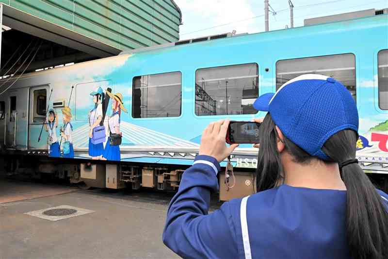 「放課後ていぼう日誌」のラッピング列車を撮影するファン＝6日、鹿児島県出水市