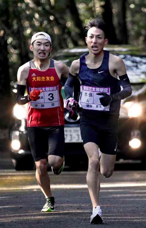 第4中継所手前で競り合う水俣市Aの磯田章太選手（右）と津奈木町Aの伊藤潤選手＝7日、津奈木町（石本智）