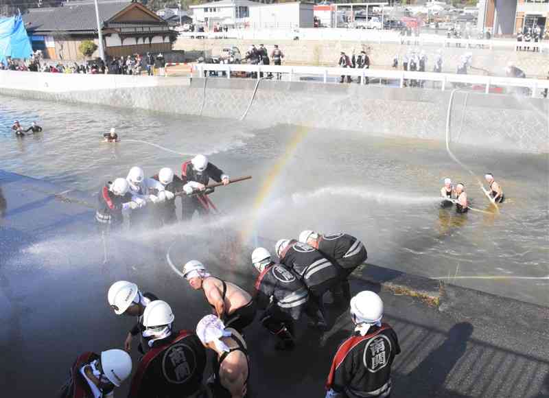 放水合戦で豪快に水を掛け合う消防団員ら＝13日、南関町