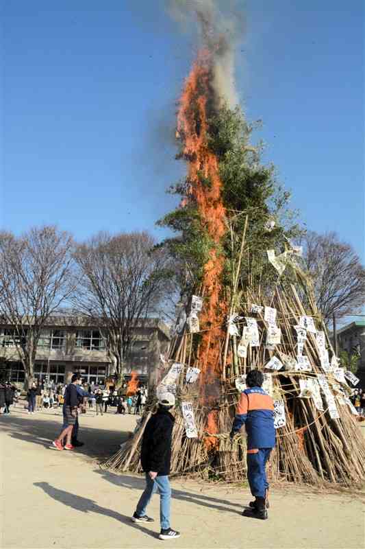 泉ケ丘小のどんどやで、やぐらに点火する児童や消防団員ら＝13日、熊本市東区