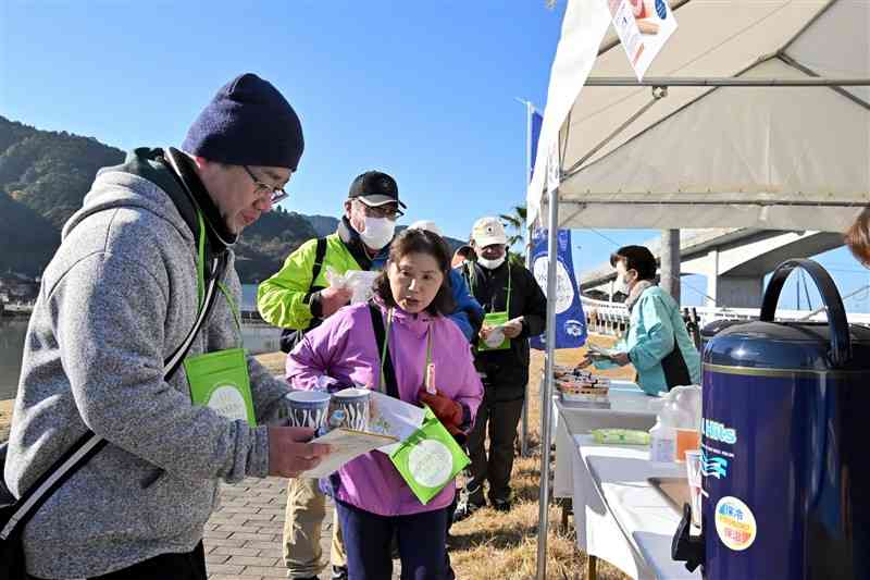 「ONSENガストロノミーウオーキング」で地元住民らのおもてなしを受ける参加者＝14日、八代市