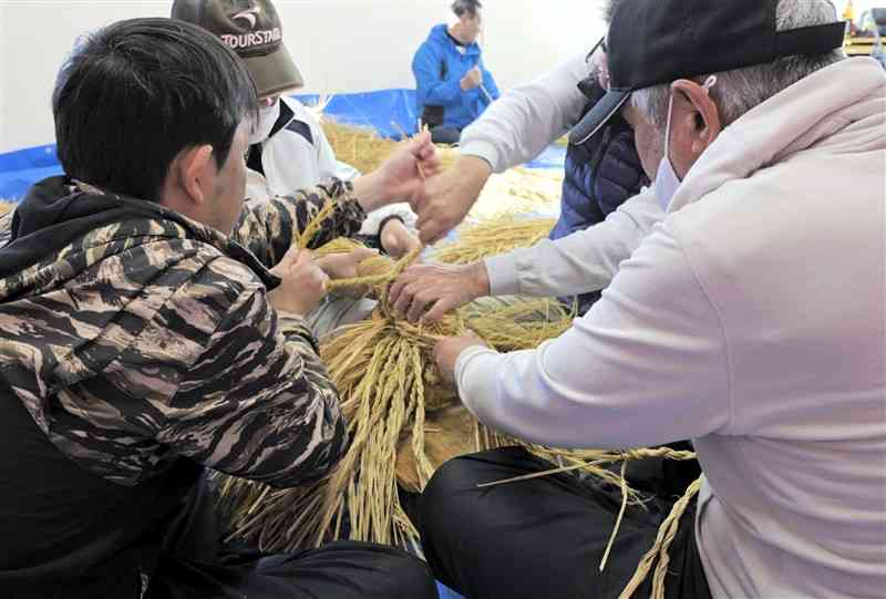より合わせたわらを4人がかりで編み込んで的を作る氏子ら＝14日、長洲町